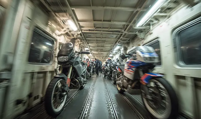 Motos arrimées dans le wagon de l’Eurotunnel avec motards en discussion