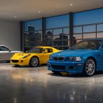 Trois sportives des années 2000 : Porsche 911 argentée, Lotus Elise jaune, BMW M3 bleue, dans un garage avec vue sur ville au crépuscule.