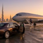 Un homme d'affaires descend d'un jet privé devant une voiture de luxe avec la skyline de Dubaï au coucher du soleil.